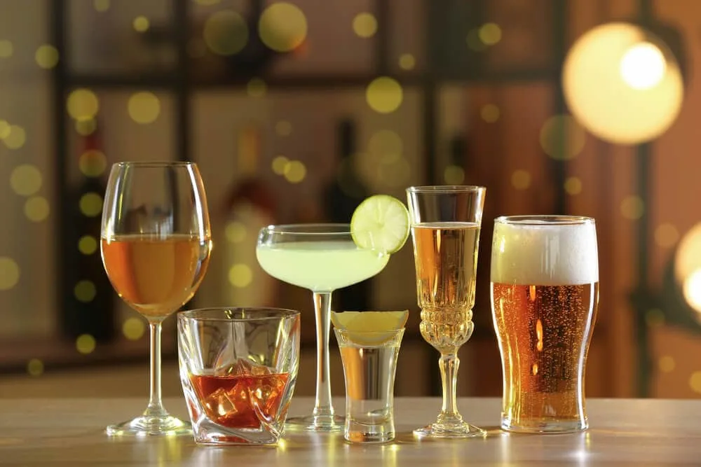 Assorted alcoholic drinks, including beer, wine, and cocktails, on a bar counter.
