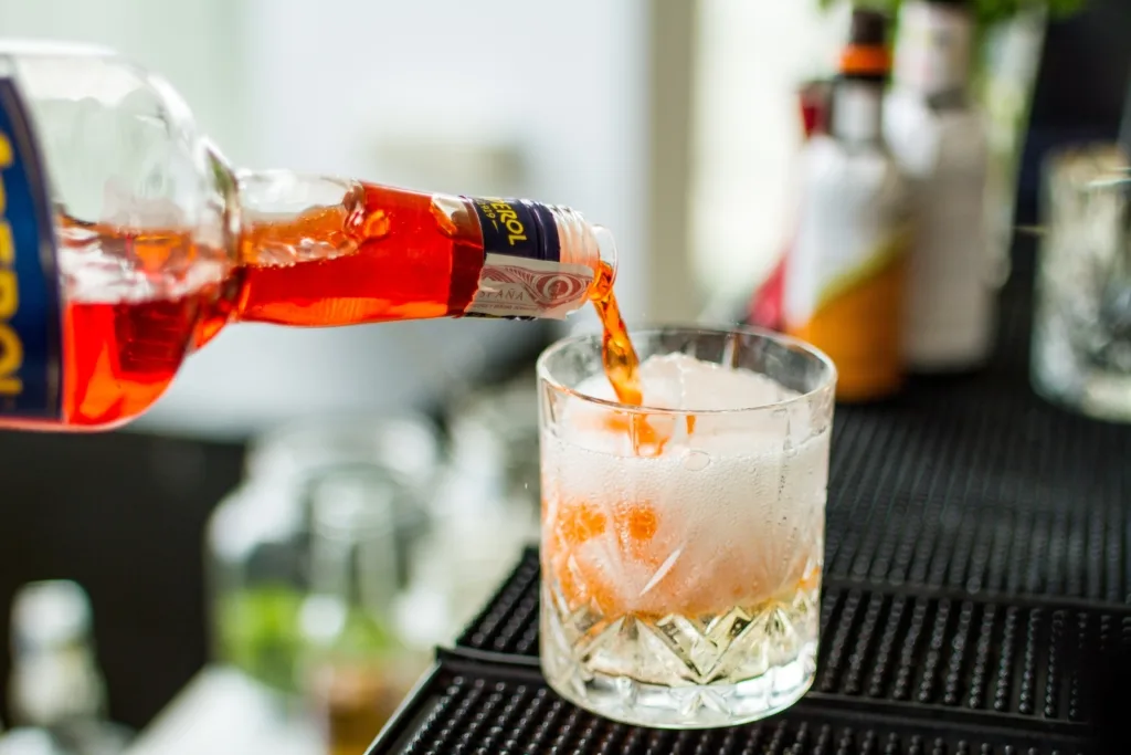 Bottle pouring a Spanish drink into a glass with ice.
