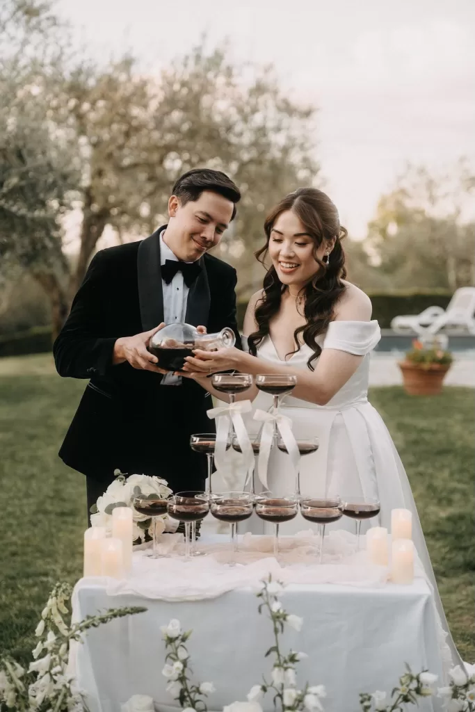 Bride and groom pouring cocktails at an outdoor wedding celebration.