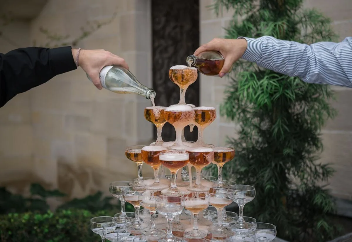Champagne tower being filled at a luxury wedding.