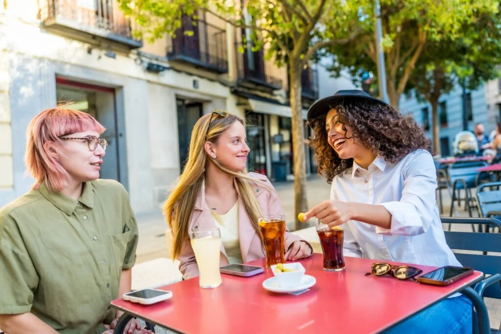 Friends enjoying drinks and conversation at an outdoor café in Spain.