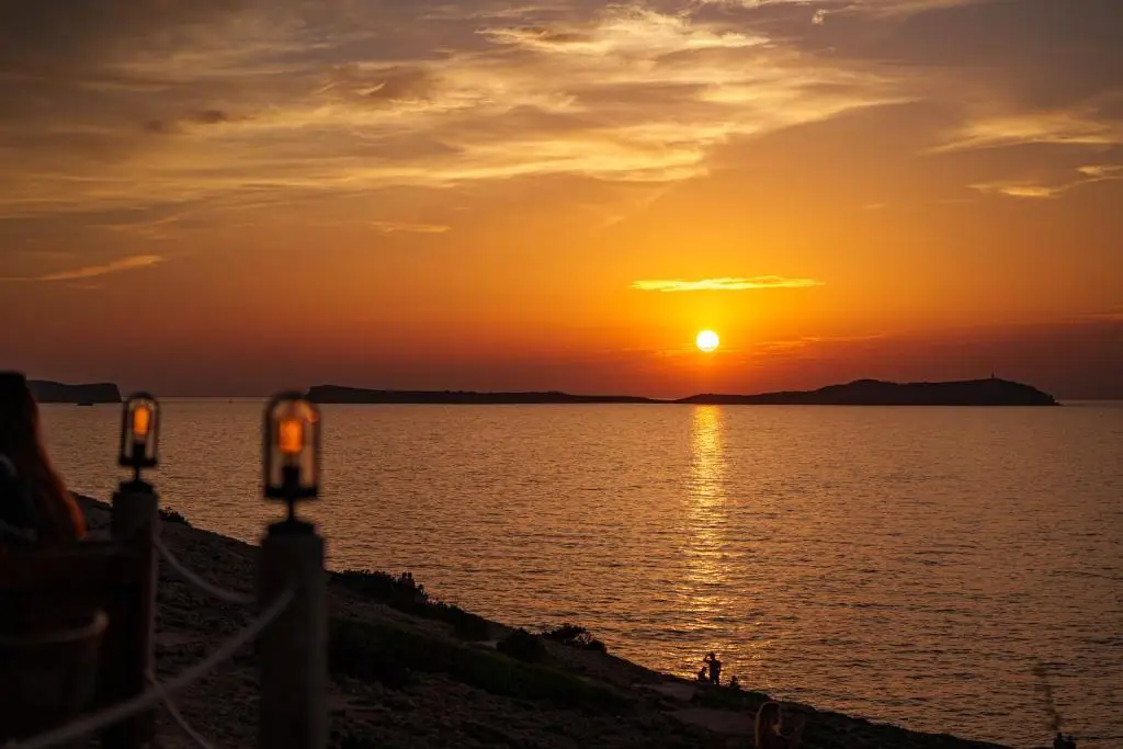 Ibiza boat party at sunset with guests enjoying drinks on the sea.