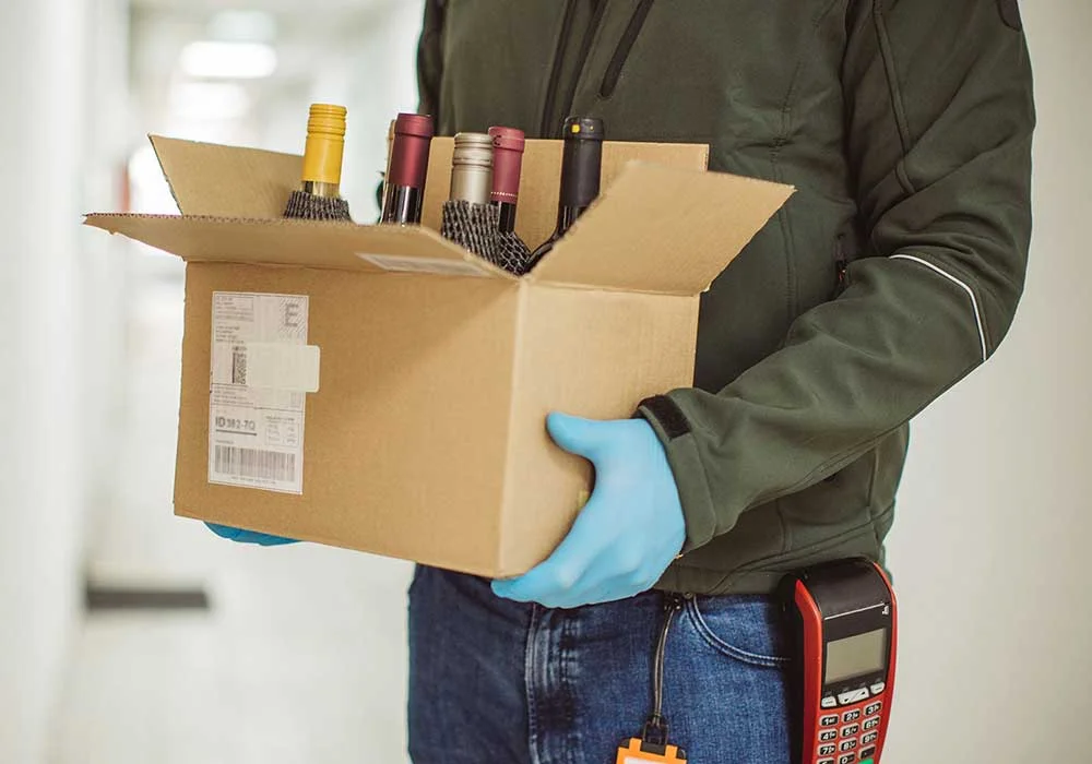 Alcohol delivery courier carrying a box of wine bottles.