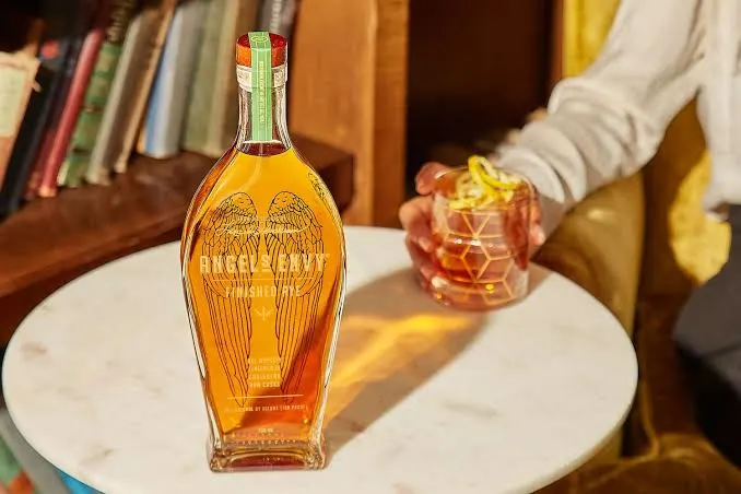 Angel’s Envy rye whiskey bottle beside a cocktail.