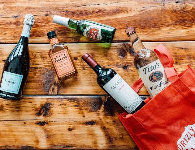 Assorted wine and spirits bottles beside a delivery bag.