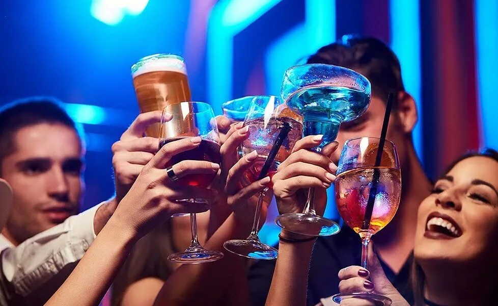 Friends raising cocktails and beer at a party.