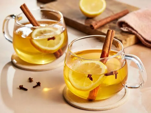 Glass cups of hot toddy drink with cinnamon sticks and cloves.