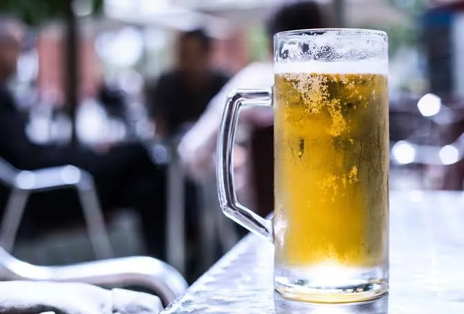 Glass mug of cold clara beer on a table in a café setting.