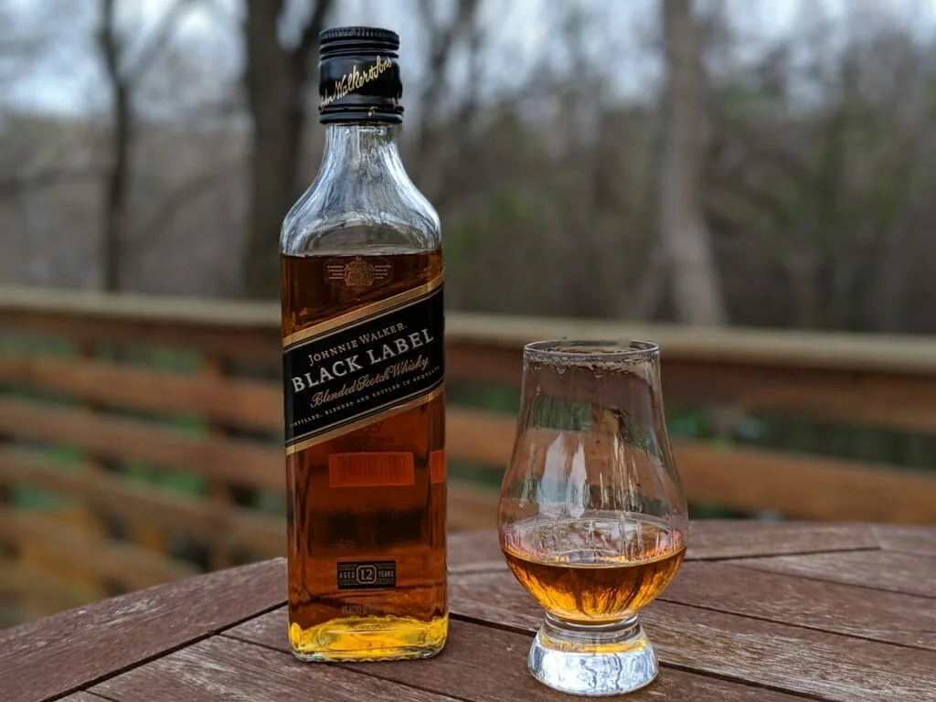 Johnnie Walker Black Label whisky bottle beside a tasting glass.