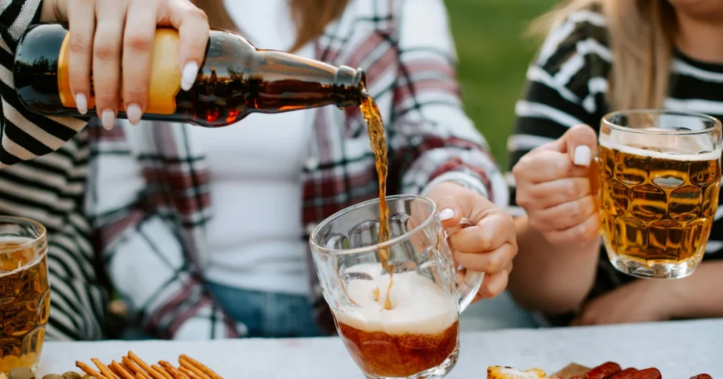 People pouring and enjoying beer at an outdoor party gathering.