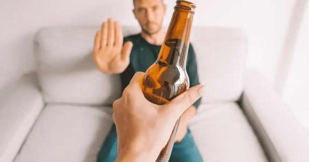 Person refusing an offered bottle of beer.