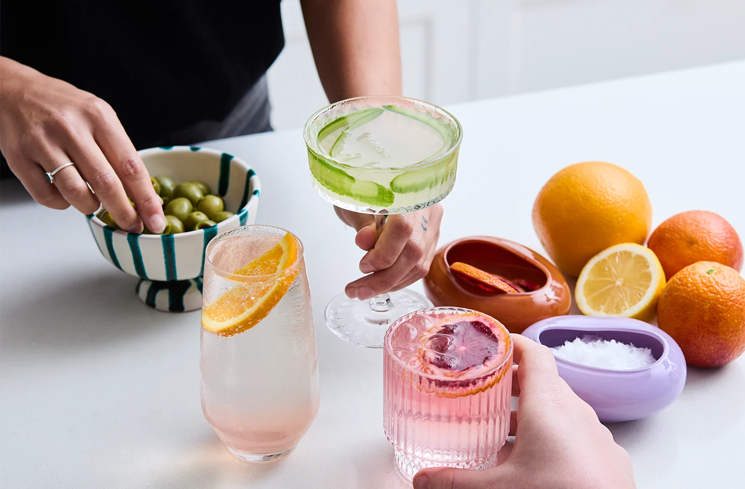 Refreshing citrus cocktails with olives and fruit garnishes.
