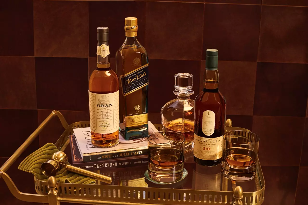 Whisky bottles and glasses on a stylish bar cart.