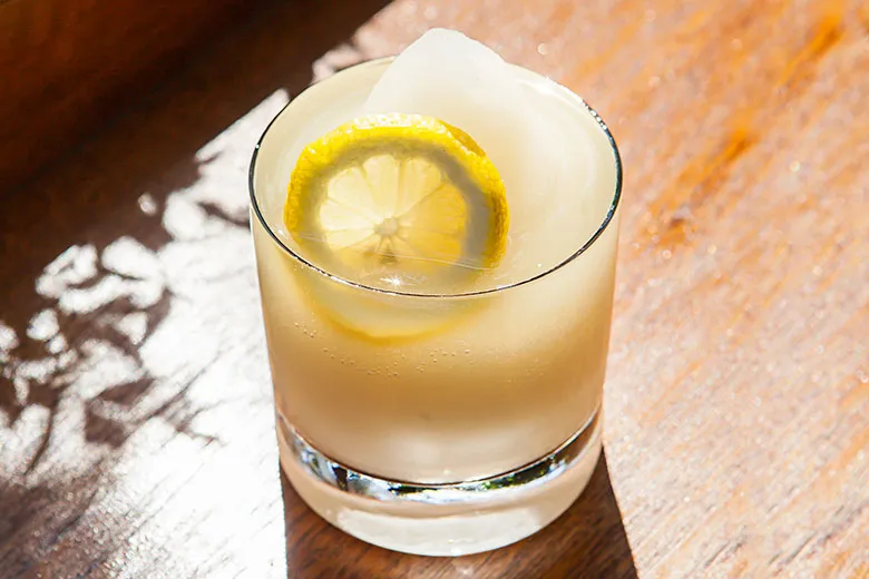 pomada with crushed ice in a glass on a wooden table.