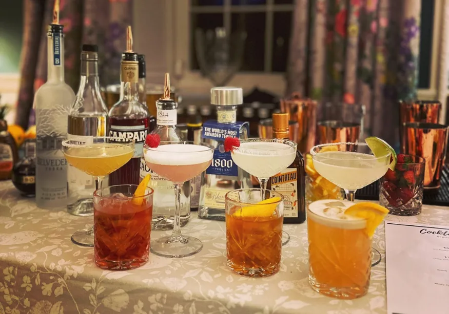 Assorted cocktails and liquor bottles arranged on a bar table.