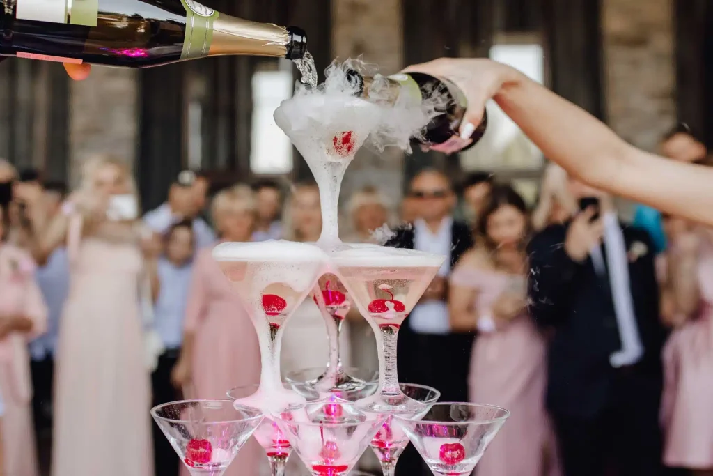 Champagne being poured over a tower of cocktail glasses at an event.