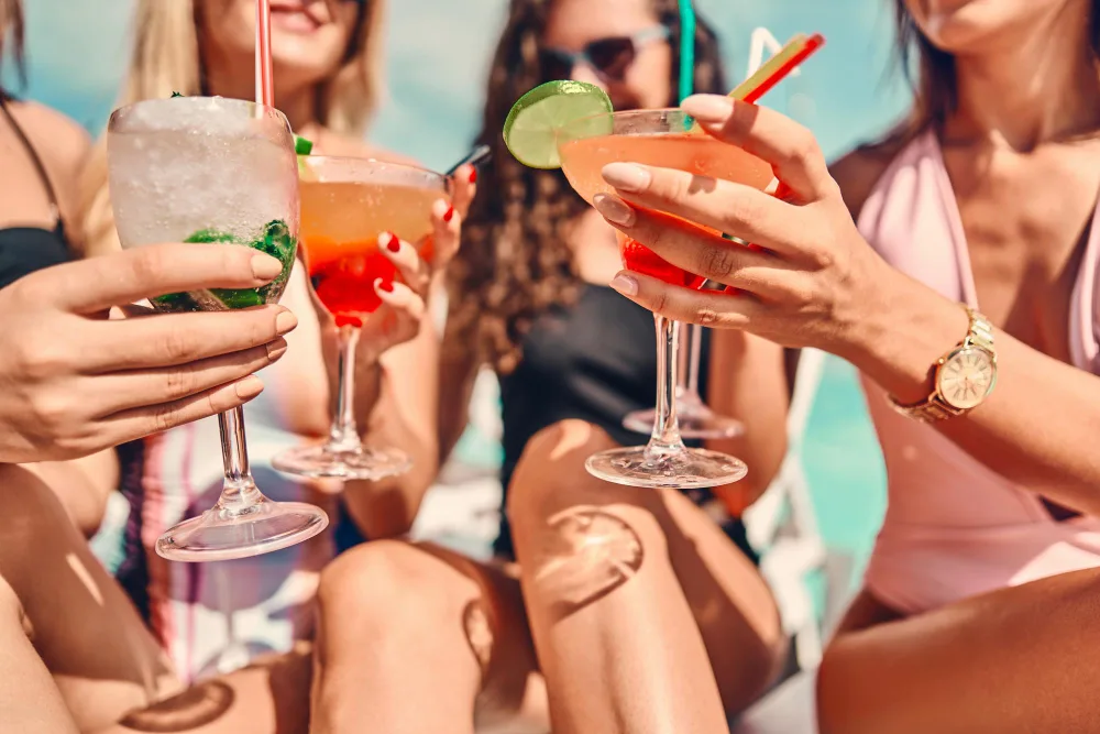 Friends enjoying colorful cocktails by the pool.