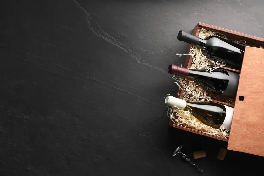 Wine bottles arranged in a wooden gift box on a dark surface.