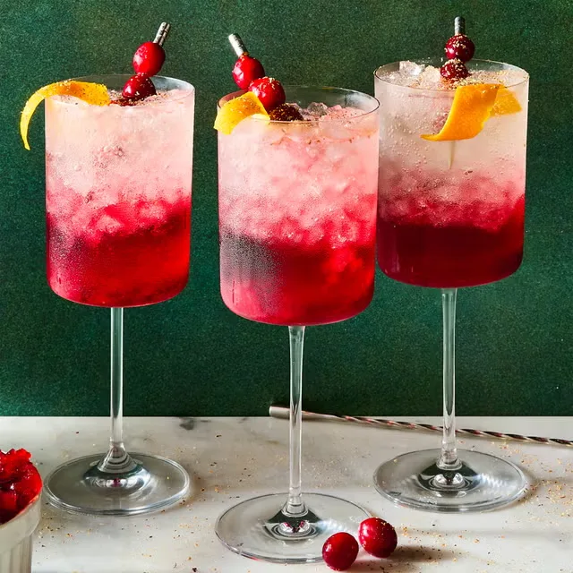 Festive cranberry Christmas cocktails with orange twists and crushed ice.