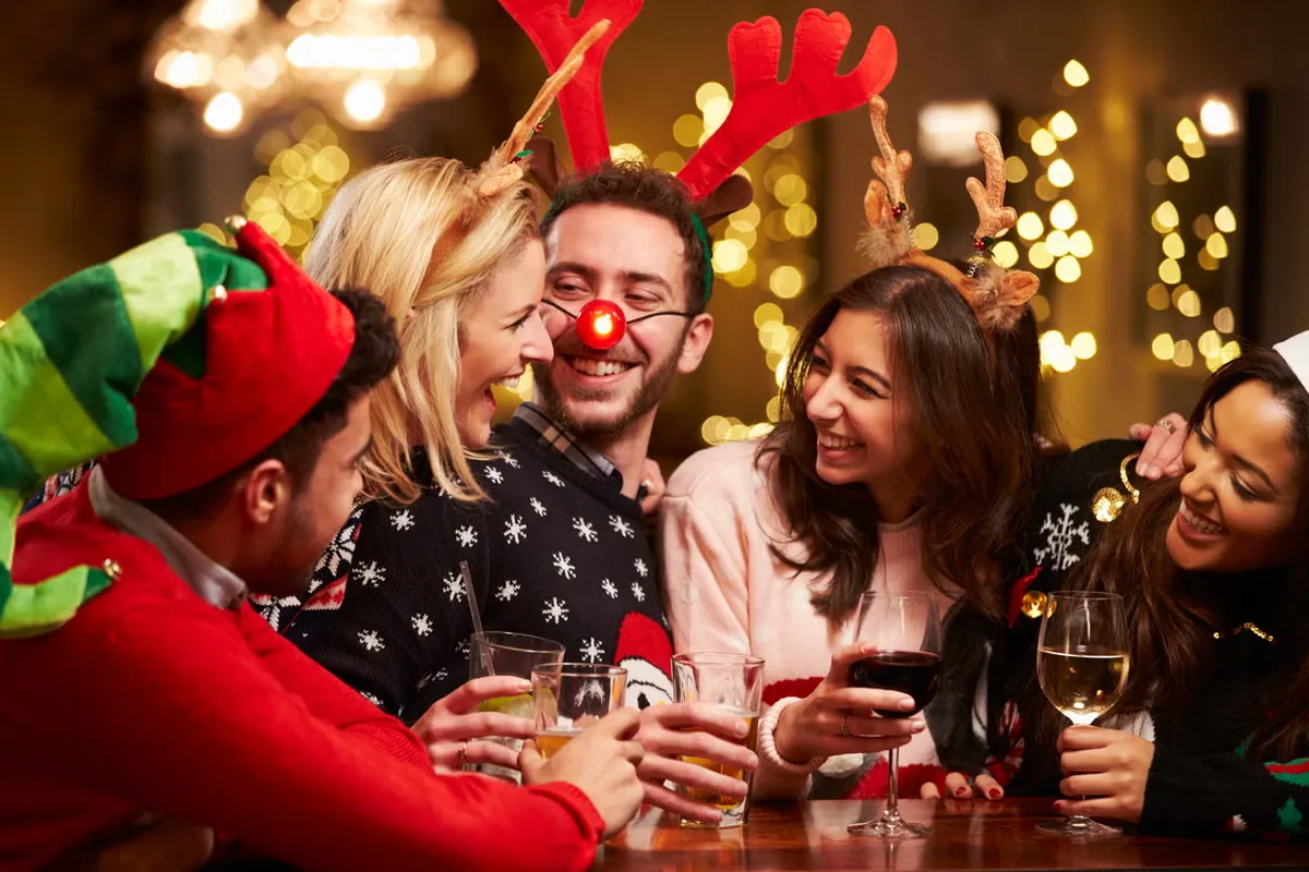 Friends enjoying Christmas drinks at a festive holiday party.