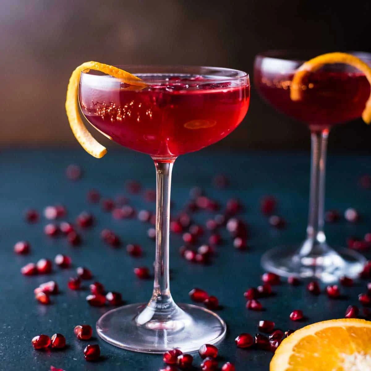 Pomegranate Christmas cocktails garnished with orange twists.