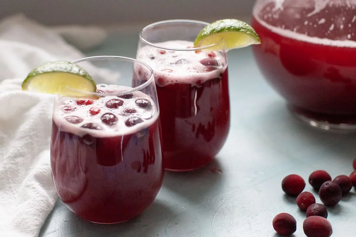 Sparkling cranberry Christmas punch with lime wedges and fresh cranberries.